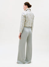Load image into Gallery viewer, A woman with a neat low bun stands facing away, wearing the Palermo Pant—high-waisted, wide-leg pants made from exquisite Italian fabric—paired with a light embroidered jacket against a plain background.