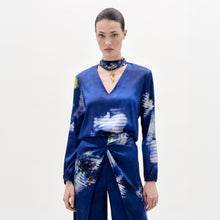 Load image into Gallery viewer, Woman wearing the Lane Blouse, a blue patterned top, paired with a matching skirt and choker necklace, standing against a plain light background.
