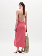 Load image into Gallery viewer, A woman stands against a plain background wearing the sleeveless pink Veracruz Dress with a gathered waist, holding a large beige fringed bag and wearing brown sandals.