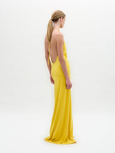 Load image into Gallery viewer, Model in the Aiko Dress—a floor-length, sleeveless yellow maxi with a deep halter neckline and gathered circular waist detail—stands against a plain white background.