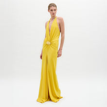 Load image into Gallery viewer, Model in the Aiko Dress—a floor-length, sleeveless yellow maxi with a deep halter neckline and gathered circular waist detail—stands against a plain white background.
