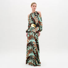 Load image into Gallery viewer, A woman wears the Carla Dress, a long patterned maxi with cut-out shoulders, a gathered neckline, long sleeves, a wide belt, and crafted from luxurious Italian fabric, standing against a plain white background.