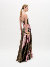 Load image into Gallery viewer, A woman poses against a plain background wearing the Carmin Dress— a floor-length, sleeveless maxi crafted from Italian fabric with a pink and olive green tie-dye pattern and a deep V neckline.