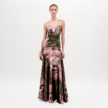 Load image into Gallery viewer, A woman poses against a plain background wearing the Carmin Dress— a floor-length, sleeveless maxi crafted from Italian fabric with a pink and olive green tie-dye pattern and a deep V neckline.