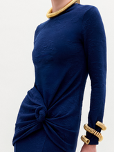 Load image into Gallery viewer, Woman wearing the Celyse Tshirt, a fitted long-sleeve navy top with front knot detail and a flattering silhouette, styled with gold jewelry against a plain white background.