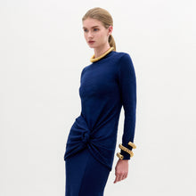 Load image into Gallery viewer, Woman wearing the Celyse Tshirt, a fitted long-sleeve navy top with front knot detail and a flattering silhouette, styled with gold jewelry against a plain white background.