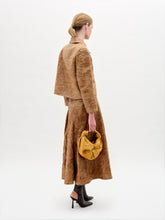 Load image into Gallery viewer, A woman wears the Olga Skirt in brown with a matching textured A-line jacket, gold accent belt, dark ankle boots, and a minimal background.
