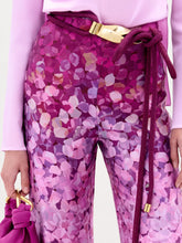 Load image into Gallery viewer, A woman wearing the Como Pant in color Magenta with a Sofia bag in color Purple on a white background.