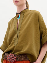 Load image into Gallery viewer, A person wearing the Daia Blouse in color Olive Opal with a brown belt on a white background.