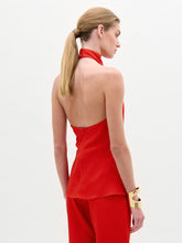 Load image into Gallery viewer, A woman stands against a plain white background wearing the lustrous hammered satin Dina Blouse, a high-neck sleeveless top, with matching red pants. Her hair is tied back and she accessorizes with a wide gold bracelet.