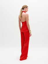 Load image into Gallery viewer, A woman poses against a white background in the sleeveless red halter top and high-waisted, wide-leg Palermo Pant in hammered satin, accessorized with gold bracelets.