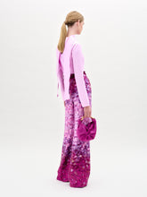 Load image into Gallery viewer, A woman stands against a plain background wearing a light pink long-sleeve top and the Como Pant—high-waisted, wide-leg pants crafted from Italian fabric—while holding a matching small bag.