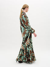 Load image into Gallery viewer, Against a plain white background, a person wears the Florina Skirt, crafted from luxurious Italian fabric. This long skirt showcases a vibrant tie-dye pattern with green, orange, and black hues cascading elegantly down its maxi length.