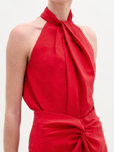 Load image into Gallery viewer, Woman wearing the Shela Blouse, a sleeveless red halter-neck top made from Italian fabric with a knotted front detail, standing against a plain light background.