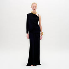 Load image into Gallery viewer, Against a plain background, a person showcases the Shiri Dress, a long black asymmetrical column silhouette crafted from Italian fabric, paired with gold accessories.