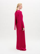 Load image into Gallery viewer, A woman poses in the Sue Dress, a vibrant pink, long-sleeved maxi made from luxurious Italian fabric with a gathered knot at the waist, set against a plain white background.