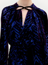 Load image into Gallery viewer, A person stands against a plain background wearing the Ximena Blouse in color eggplant velvet