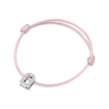 Load image into Gallery viewer, The L'Arc Voyage Charm PM bracelet from the Paris Atelier showcases a delicate silk cord in pink and a white gold charm adorned with Galerie diamonds. The bracelet features adjustable knots, offering a simple and elegant design.