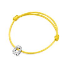Load image into Gallery viewer, The L'Arc Voyage Charm PM bracelet exudes Paris Atelier elegance with its yellow silk cord featuring a knot on each side. At the heart of this piece, a dazzling 18k white gold charm encrusted with Galerie diamonds sparkles, hanging prominently in the center.