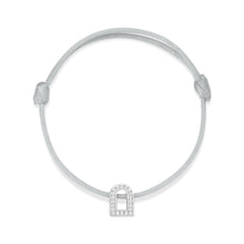 Load image into Gallery viewer, Introducing the L'Arc Voyage Charm PM bracelet: a minimalist piece designed with an adjustable thin gray silk cord and featuring an 18k white gold charm resembling a padlock, elegantly adorned with Galerie diamonds, inspired by the sophistication of Paris Atelier.