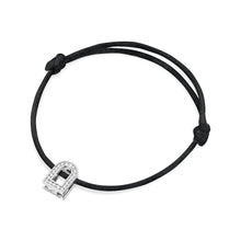 Load image into Gallery viewer, The L'Arc Voyage Charm PM bracelet showcases an elegant charm crafted from 18k white gold and embellished with Galerie diamonds, all set on a delicate black silk cord. Reminiscent of a Paris Atelier, this adjustable bracelet features simple knots on each side, exuding a minimalist design with classic sophistication.