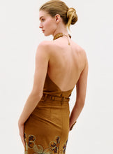 Load image into Gallery viewer, A woman with blonde hair in a low bun wears the Ann Blouse, featuring an open back and embroidered floral details, standing against a plain light background.
