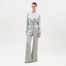 Load image into Gallery viewer, A woman with her hair pulled back and a neutral expression stands against a plain light background, wearing the Palermo Pant—light gray, wide-leg style—paired with a matching long-sleeve wrap-front top and open-toe heels.
