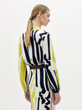 Load image into Gallery viewer, A woman poses against a plain background wearing the Honey Blouse, featuring long sleeves and a deep V-neck with black, white, yellow, and red stripes, styled with a wide belt.
