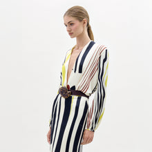 Load image into Gallery viewer, A woman poses against a plain background wearing the Honey Blouse, featuring long sleeves and a deep V-neck with black, white, yellow, and red stripes, styled with a wide belt.
