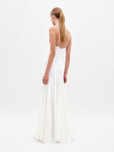 Load image into Gallery viewer, A woman in the Sana Dress White, featuring a sleeveless design with a deep V-neck and floral detail at the waist, stands against a plain white background. Pre-order now to ensure delivery by February 15th, 2025.

