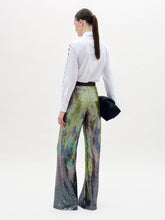 Load image into Gallery viewer, A person stands against a plain background wearing a white button-up shirt and the high-waisted, multicolored sequin Dalal Pant, holding a black clutch in their left hand.
