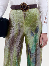 Load image into Gallery viewer, A person stands against a plain background wearing a white button-up shirt and the high-waisted, multicolored sequin Dalal Pant, holding a black clutch in their left hand.
