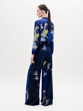 Load image into Gallery viewer, A person stands against a white background wearing the Canturipe Pant, paired with a blue patterned satin blouse and a choker-style scarf.
