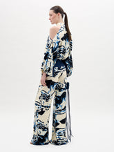 Load image into Gallery viewer, A woman stands against a plain white background wearing a cream and navy blue marble-patterned halter top with matching Como Pants in a wide-leg style.
