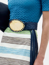 Load image into Gallery viewer, The Kai Belt is a black braided belt with a large oval gold buckle and long black fringe hanging down one side, shown on a plain light grey background.
