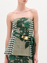 Load image into Gallery viewer, A woman wears the Astor Top, a strapless bustier in green, beige, and houndstooth Italian fabric with a matching skirt and a green belt with gold clasp, standing against a plain white background.
