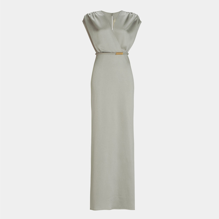 The Freda Dress is a sleeveless, floor-length light gray maxi dress with a V-neckline, gathered shoulders, and a slim waist belt, crafted from luxurious Italian fabric for a refined, fitted silhouette.