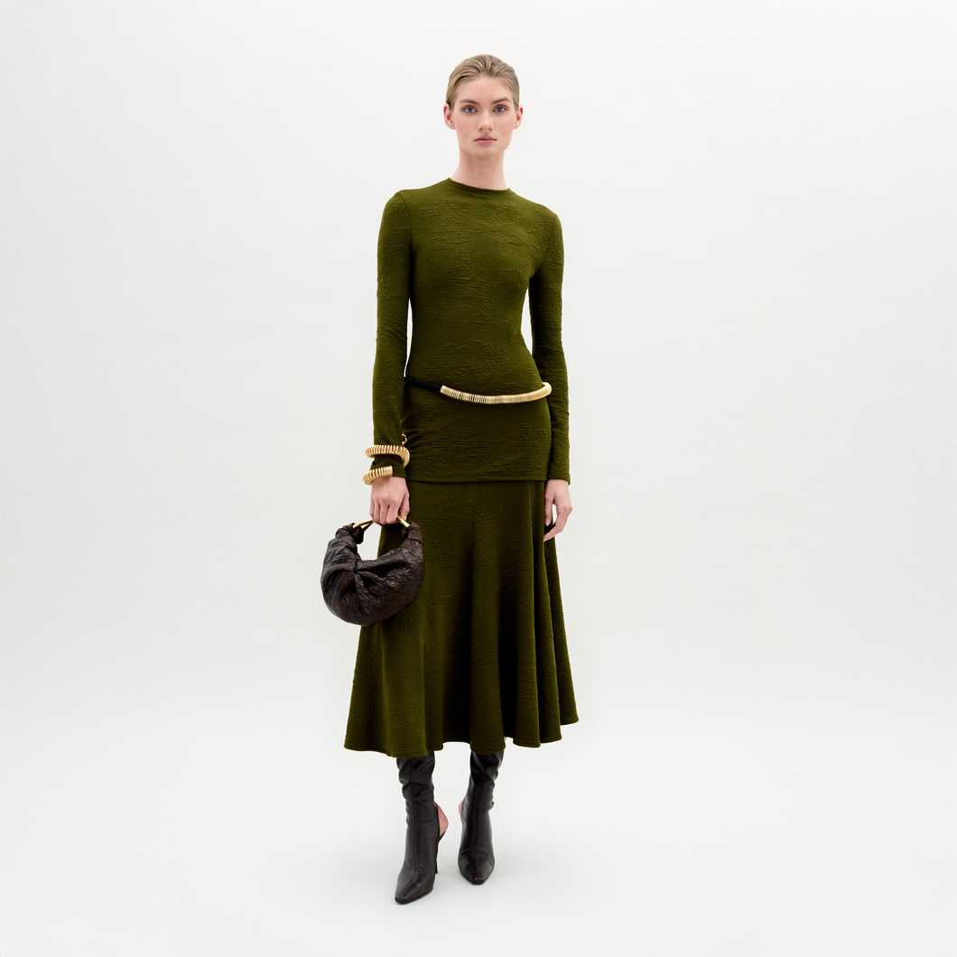 Woman wearing a green outfit with a skirt and sweater on a white background
