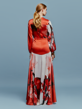 Load image into Gallery viewer, A person is wearing the Keira Dress in Pomegranate Abstract Flowers, featuring long sleeves and a floral print, standing against a plain blue background as if ready for the upcoming events on August 19th.
