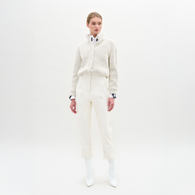 Load image into Gallery viewer, A person stands against a plain light background, wearing a textured white sweater, white collared shirt, the Moad Pant—an Italian fabric high-waisted cropped pant—and white heeled boots.
