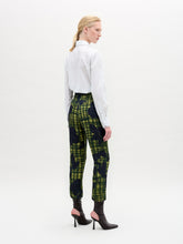 Load image into Gallery viewer, Against a neutral backdrop, a person models a chic outfit with the Naroa Blouse in Italian white patterned fabric, styled with green and blue patterned pants. The ensemble is completed by sleek black high-heeled boots.
