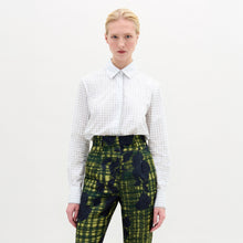 Load image into Gallery viewer, Against a neutral backdrop, a person models a chic outfit with the Naroa Blouse in Italian white patterned fabric, styled with green and blue patterned pants. The ensemble is completed by sleek black high-heeled boots.

