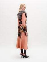 Load image into Gallery viewer, A person stands in profile wearing the Pesaro Dress—a peach silk midi with a large feathered design, wide belt with round buckle, gray fur collar, and black heeled boots—set against a plain background.
