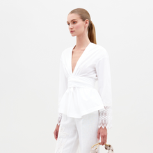Load image into Gallery viewer, Person wearing the Saanvi Blouse White with lace detail and coordinating white pants, holding a small handbag, looking off to the side against a plain background. Don't miss your chance to pre-order this stunning outfit by the ship-by date of February 15th, 2025.
