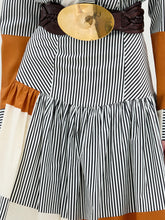 Load image into Gallery viewer, Black and white striped dress with a brown belt and gold buckle on a wooden surface.
