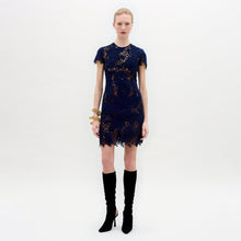 Load image into Gallery viewer, A woman wearing the Veronica Dress in color Navy with a golden bracelet on a white background.
