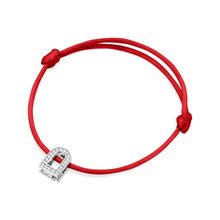 Load image into Gallery viewer, Introducing the L'Arc Voyage Charm PM bracelet from our Paris Atelier. This elegant accessory features a delicate silk cord in red with an adjustable knot, paired with a small padlock-shaped charm crafted from 18k white gold. The charm is beautifully adorned with Galerie diamonds, adding an extra touch of sparkle to this simple yet sophisticated piece.
