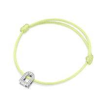 Load image into Gallery viewer, The L'Arc Voyage Charm PM is a refined bracelet featuring a vibrant silk cord in yellow with an adjustable knot and an 18k white gold Paris Atelier padlock charm. This charm is embellished with Galerie diamonds, lending a sophisticated elegance to the minimalist design.
