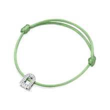 Load image into Gallery viewer, The L'Arc Voyage Charm PM bracelet, crafted with 18k white gold and Galerie diamonds, is a delicate piece featuring a green silk cord and an elegantly designed horseshoe charm, reminiscent of the exquisite craftsmanship found in a Paris atelier.
