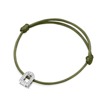 Load image into Gallery viewer, The L'Arc Voyage Charm PM is a silk cord bracelet in green, featuring an elegant 18k white gold lock-shaped charm adorned with Galerie diamonds. It is intricately crafted in the sophisticated Paris Atelier and secured with simple knots framing the charm.
